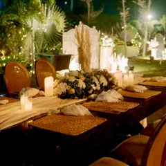 An intimate long table setup for the 25th anniversary dinner. We used woven placemats, a simple runner, and a centerpiece of white flowers and candles to create a warm and elegant dining experience.