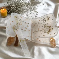 This is my resin holy book stand, or rihal, designed to be both beautiful and functional. I've embedded delicate sprigs of baby's breath and scattered gold flakes into the clear resin, creating a serene and elegant piece for your daily prayers or reading. It also comes with a matching bookmark.
