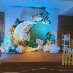 A unique moon and stars theme featuring adorable elephant cutouts and a picket fence. The color scheme of sage green, beige, and white gives this baby shower decoration a gentle and soothing feel.