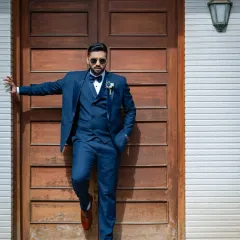 A sharp and stylish portrait of the groom. The bold blue suit and cool pose against the rustic door make for a modern and confident shot.