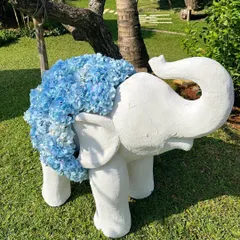A close-up of a baby elephant sculpture covered in beautiful blue hydrangeas, adding a touch of artistry and sweetness to the outdoor ceremony decor.