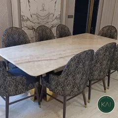 A luxurious eight-seater dining table with a polished marble top and a geometric brass base. We paired it with chairs upholstered in a sophisticated patterned fabric to create a truly opulent dining experience for our client.