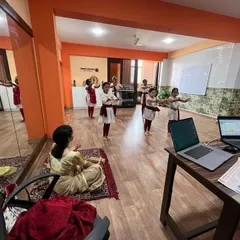 An instructor demonstrates a dance move, visible to both the students in the studio and those joining via video call. We ensure every student can clearly see the practical demonstrations.