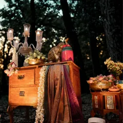 A magical reception backdrop created using three identical dupattas from the bride's mother's collection. We draped them over antique furniture and adorned the scene with brass lamps, lotus buds, and Channapatna crafts for a truly personal touch.