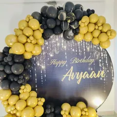 A close-up of the custom backdrop and the rich gold and black balloon arrangement.