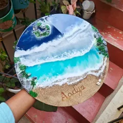 A finished personalized resin nameplate for 'Aadya'. This piece features a heart-shaped island and gentle waves on a round wooden base, capturing a peaceful beach scene.