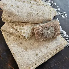 We present our heirloom Chikankari saree, a testament to opulent craftsmanship. Rendered on off-white crepe, this made-to-order piece is heavily highlighted with mirrorwork, Kutdana, and sequins, and is styled here with a complementary clutch for a complete festive look.