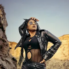 This image captures a bold, edgy aesthetic for an outdoor fashion campaign. The model's strong pose in a black leather outfit against a rugged rock formation demonstrates our ability to create powerful, narrative-driven visuals on location.