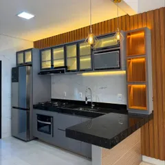 A stunning grey kitchen with a breakfast bar extension. The design features wood paneling and integrated lighting, creating a warm and inviting focal point in this open-plan space.