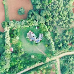 An aerial view of a farmhouse project that I designed to live in harmony with its surroundings. The unique C-shaped structure wraps around a central courtyard, creating a private oasis that is completely integrated with the lush green landscape.