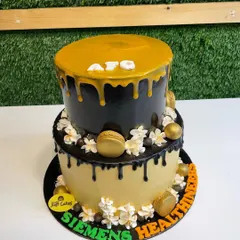 A 4kg two-tiered corporate cake with black and gold drip effects, decorated with golden macarons.