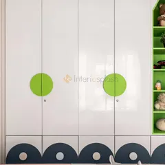 A close-up of the glossy white wardrobe in the kid's room, featuring playful green circular handles and a decorative scalloped base in dark blue.