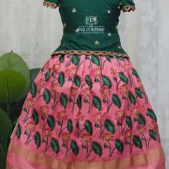 A classic Pattu Pavadai with a modern twist. The green blouse is paired with a pink skirt featuring a beautiful lotus Kalamkari print.