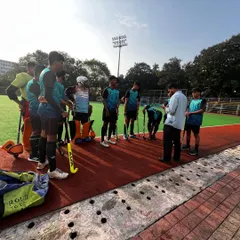 Our coach gives a pre-game briefing to the team at the B.K. Mohite Memorial Hockey Tournament. Strategy and motivation are key components of our competitive success.