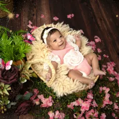 A happy baby girl surrounded by a sea of pink flowers. Her bright smile and the whimsical butterflies create a truly magical and joyful garden scene.