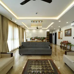 This living room combines modern comfort with traditional touches. Neutral-toned sofas are paired with classic wooden furniture and a sophisticated false ceiling design, creating a bright and airy space for the family to gather.