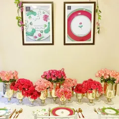 A detailed look at a tablescape for KIKA's Lotus Collection launch, featuring a beautiful arrangement of pink and red carnations in gold vases. The table setting coordinates perfectly with the brand's pink and green dinnerware, creating a cohesive and elegant presentation.