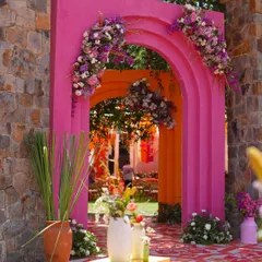 A grand entrance for a vibrant Haldi. We used bold pink and orange arches, adorned with cascading florals, to frame the pathway and create a stunning first impression for guests arriving at the celebration.