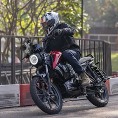 A panning shot of the red Revolt motorcycle on the track. This technique blurs the background slightly, emphasizing the bike's movement and sleek design.