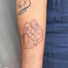 A delicate line-art portrait capturing a tender moment between a couple. This tattoo transforms a personal photograph into a timeless piece of art, celebrating love and commitment.