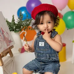A little artist deep in thought. Paint smash sessions are a fantastic and colorful alternative to cake smashes, allowing toddlers to explore their creativity and make a beautiful mess.
