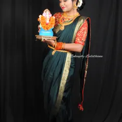 A festive Marathi look for Ganesh Chaturthi. The model is holding a Ganesha idol, and her makeup and attire reflect the celebratory spirit of the festival.