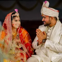 The couple shares a sweet, smiling glance during their wedding ceremony. The groom's respectful 'namaste' gesture and the bride's happy expression capture a moment of mutual love and reverence.