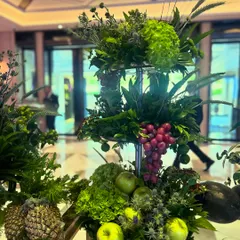 Even the smallest details of a dessert table are an opportunity for artistry. This tiered stand is decorated with fresh green apples, grapes, and pineapples, integrating fruit directly into the floral arrangement to complement the sweet offerings.