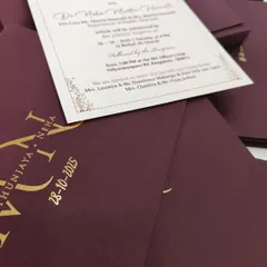 This shot reveals the invitation insert with its delicate gold border, contrasting beautifully with the deep portwine envelope.