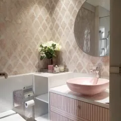 A pink powder room can be incredibly warm and inviting. In this design, we paired soft pink patterned tiles with a matching basin and fluted vanity to create a space that feels chic, modern, and welcoming.