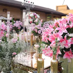 An elaborate floral and candle arrangement. The mix of pink lilies, baby's breath, and tall candles creates a stunning and romantic centerpiece.