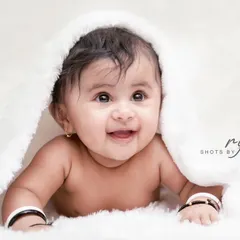 A three-month-old baby girl with the most heart-melting smile. We love capturing these simple, beautiful portraits on a soft white background.