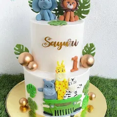 This two-tier jungle safari cake is perfect for a "Wild One" first birthday. It's decorated with a variety of handmade fondant animals, including a jeep full of critters, all on a clean, white whipped cream base.