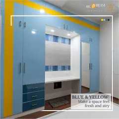 This custom floor-to-ceiling wardrobe in blue and yellow laminate includes a built-in study nook. The design provides ample storage for clothes and books while creating a dedicated, well-lit space for work or study.