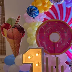 Fun and oversized props for a candy-themed party, including large cutouts of a donut and an ice cream cone next to a light-up number '1'.