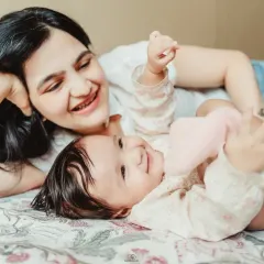 A series of candid shots from an in-home lifestyle session. A mother and her baby are playing and laughing on a bed, showcasing the natural, joyful moments I aim to capture.