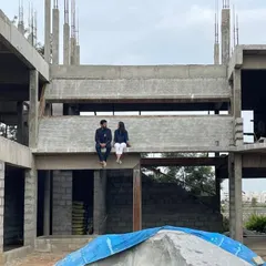 A moment of pause on site, sitting on a concrete beam of a house under construction. This is where the vision starts to take shape, and we can truly feel the scale and form of the future home.