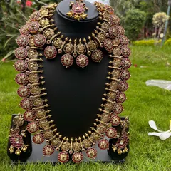 An antique-finish coin necklace set with red stones. This rental includes a choker, a long haaram, and matching earrings.