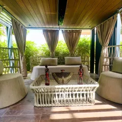 The symmetrical arrangement of the furniture inside the pergola creates a balanced and inviting composition. The open view connects the lounge directly with the surrounding garden.