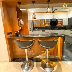 A close-up of the breakfast bar seating, highlighting the decorative pendant lights and the detailed craftsmanship of the wooden joinery.
