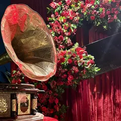 A close-up of the vintage details from the musical night. The antique gramophone paired with a lush arch of red flowers created a stunning focal point.
