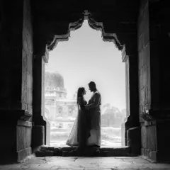 A striking black and white silhouette of a couple framed within an ornate archway. This artistic shot uses contrast and architecture to create a dramatic and romantic pre-wedding photograph.