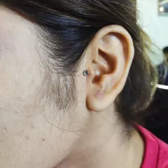 A tragus piercing, located on the small piece of cartilage in front of the ear canal, done with a crystal stud.
