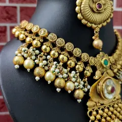 A close-up of the necklace, showing the detailed texture and the small pearl accents.