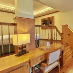 This duplex suite in Gangtok features a dedicated work desk overlooking the lower seating area. The design maximizes space while maintaining a warm, residential feel with its extensive use of wood.