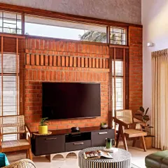 A floor-to-ceiling exposed brick wall serves as the perfect rustic backdrop for a modern TV unit, creating a beautiful contrast of textures.