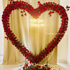 We love creating unforgettable proposal moments. This giant heart-shaped arch made entirely of fresh red roses, complete with a custom "Will You Marry Me" neon sign, makes for a definite yes.