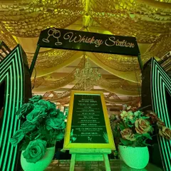 A close-up of a 'Whiskey Station' with a custom menu on an easel, flanked by floral arrangements, showing our attention to personalized details.
