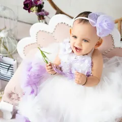 A sweet, happy moment from a first birthday photoshoot. Her genuine smile and the beautiful, soft lighting make this a perfect milestone memory.