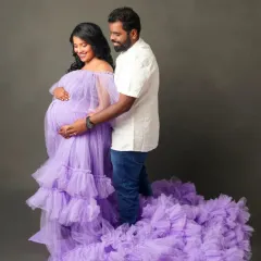 A tender moment captured in a sea of lavender tulle. This off-the-shoulder gown with its voluminous ruffled train is perfect for romantic couple's maternity portraits.